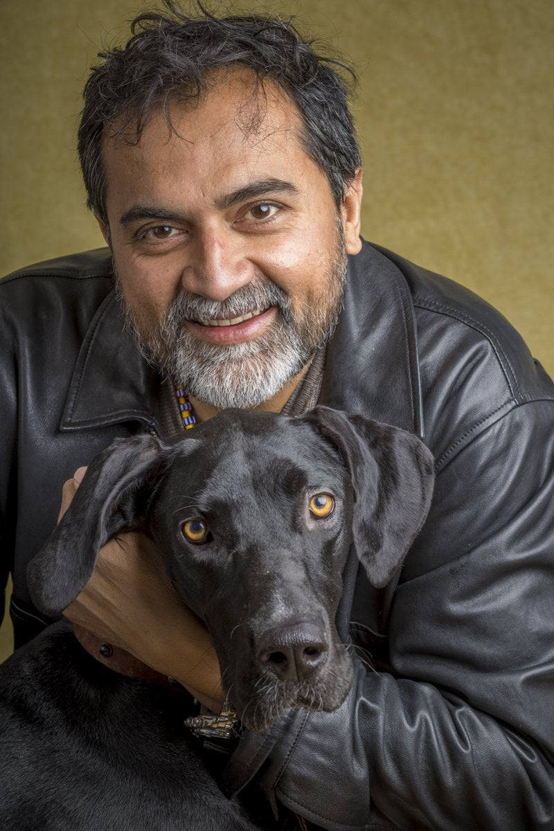 A smiling man with a grey beard holds his black Great Dane.