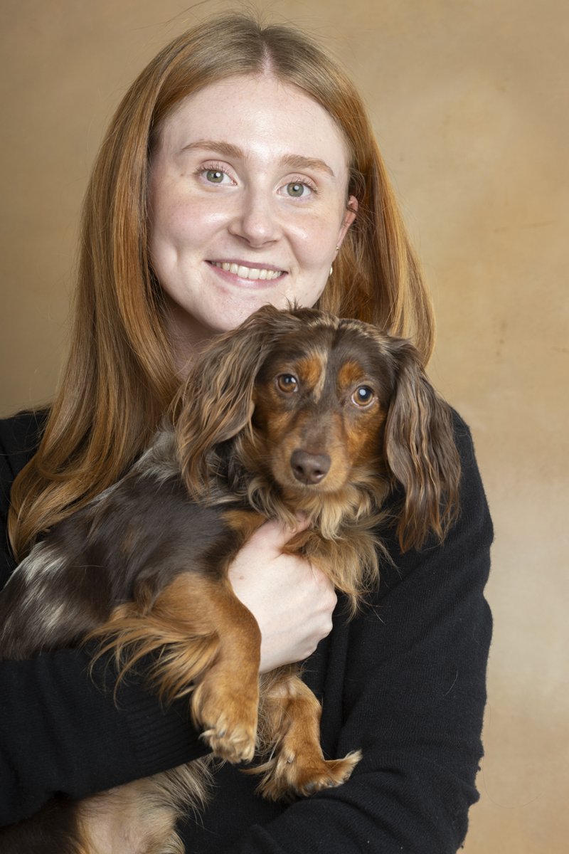 A smiling woman with red hair holds her long-haired dachshund.
